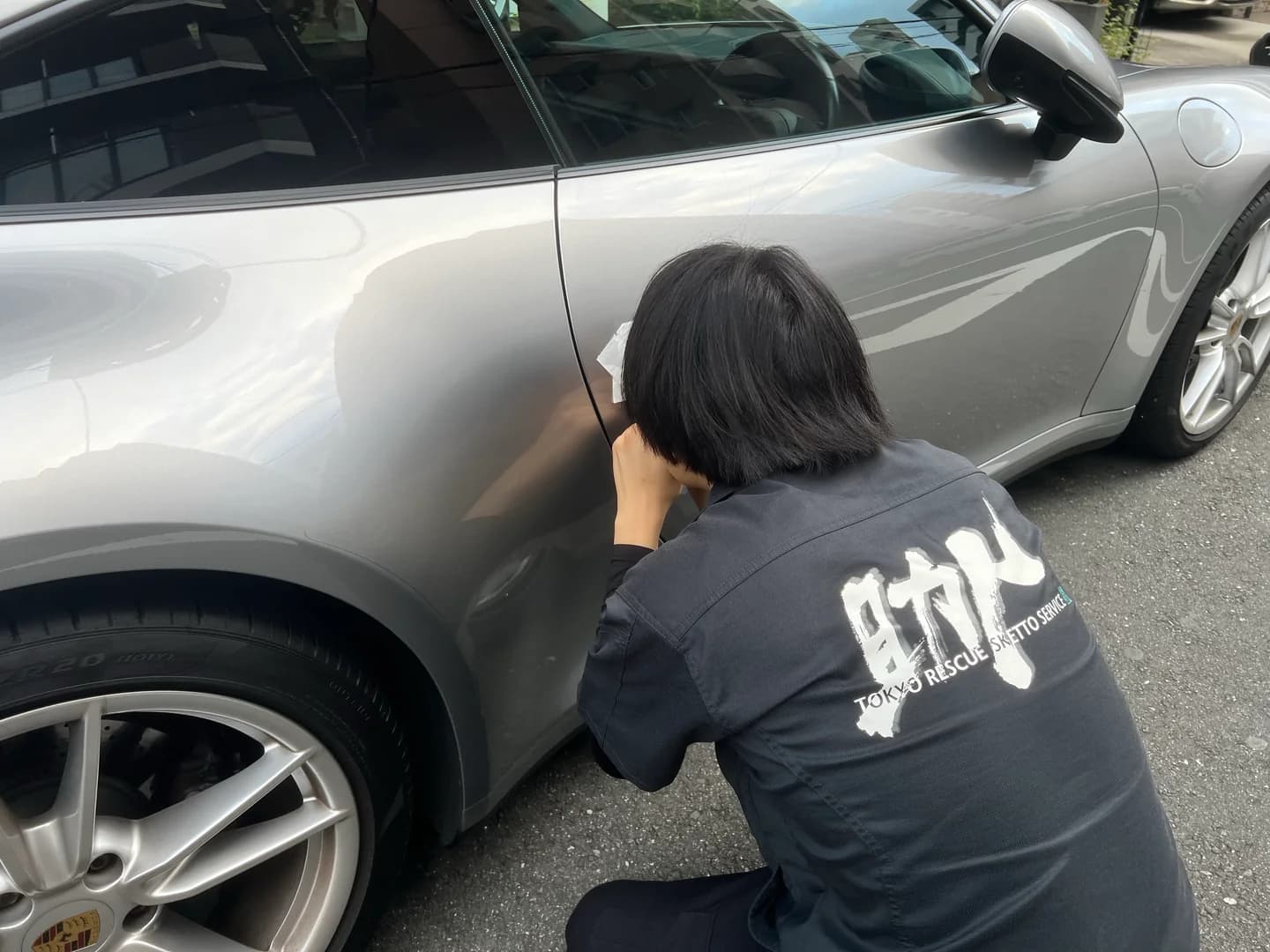 助人のウェアを着た隊員が車両のドアで開錠作業を行う様子