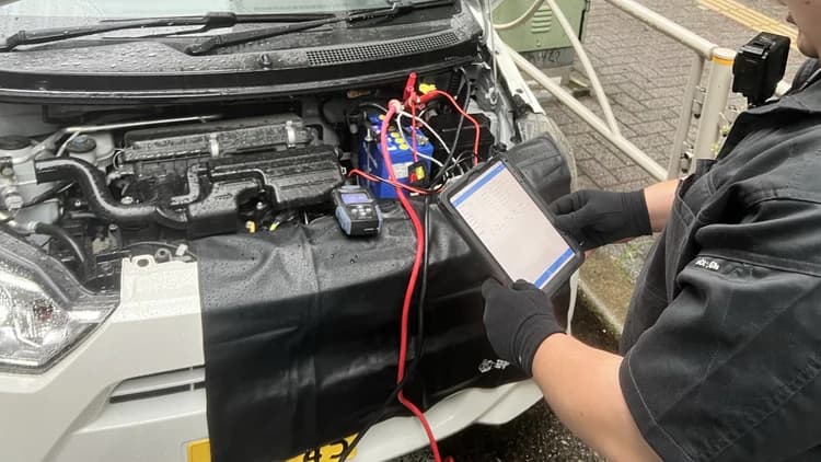 手袋を着用し、バッテリーに接続した測定機器とタブレットを確認する隊員